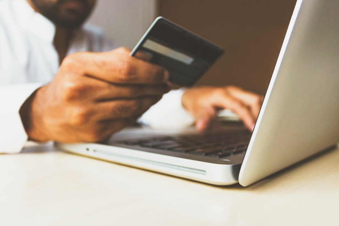 Stock photo of the Business Man with a credit card by rupixen person using laptop computer holding card