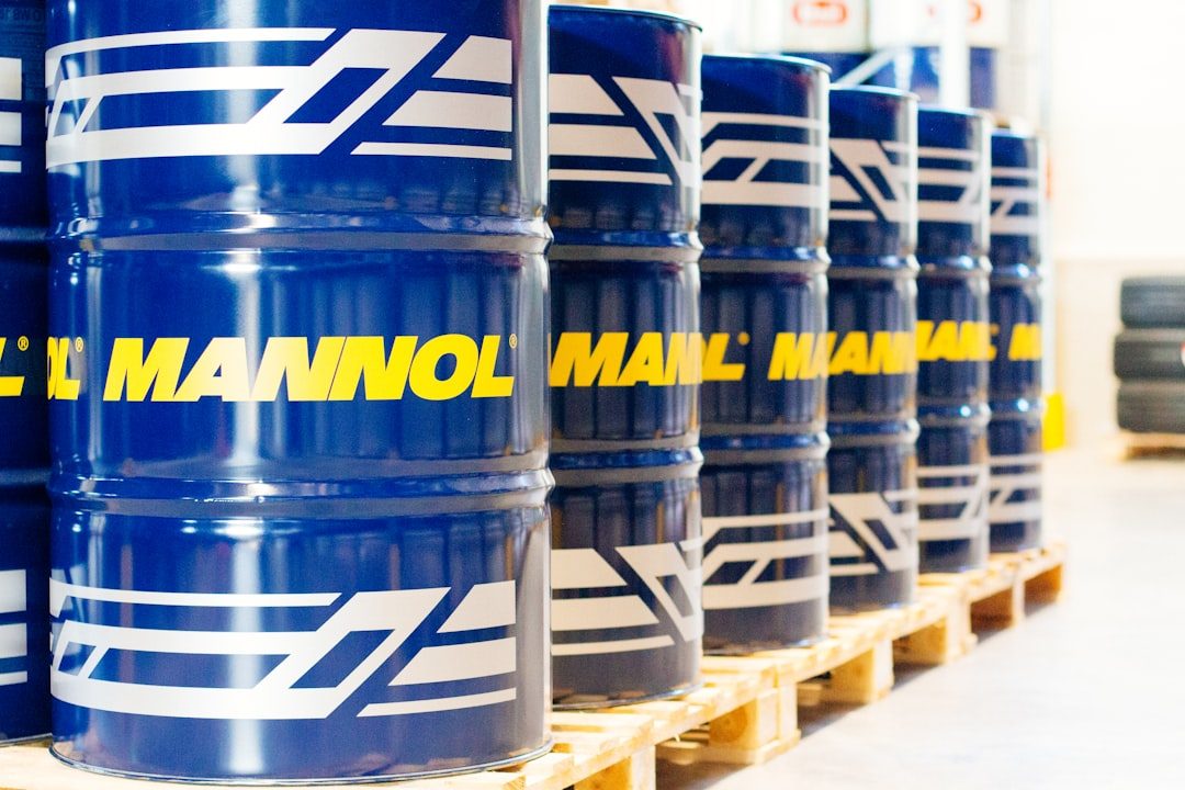 Mannol oil drums, oil barrels in warehouse for industrial editorials, marketing materials. a row of blue barrels sitting on top of pallets
